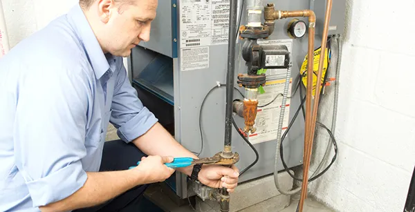 Technician repairing a furnace gas line using a wrench
